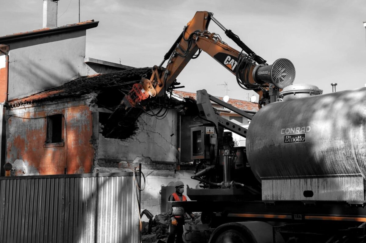Demolizione di un edificio con escavatore e cannone su autocisterna